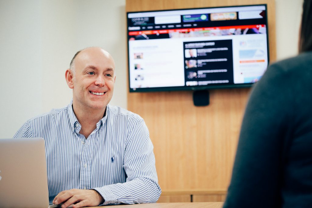 Andrew sat at desk smiling