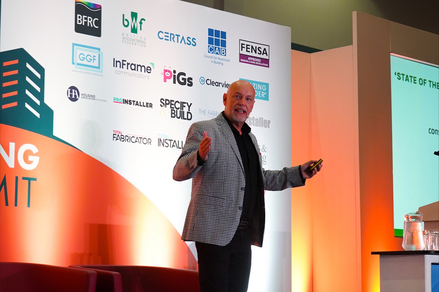Andrew Scott, standing on a bright stage delivering a presentation at the Glazing Summit event
